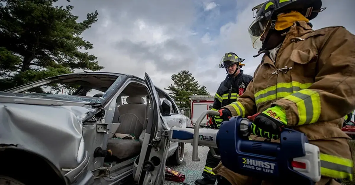 Firefighters using rescue equipment on a crashed car