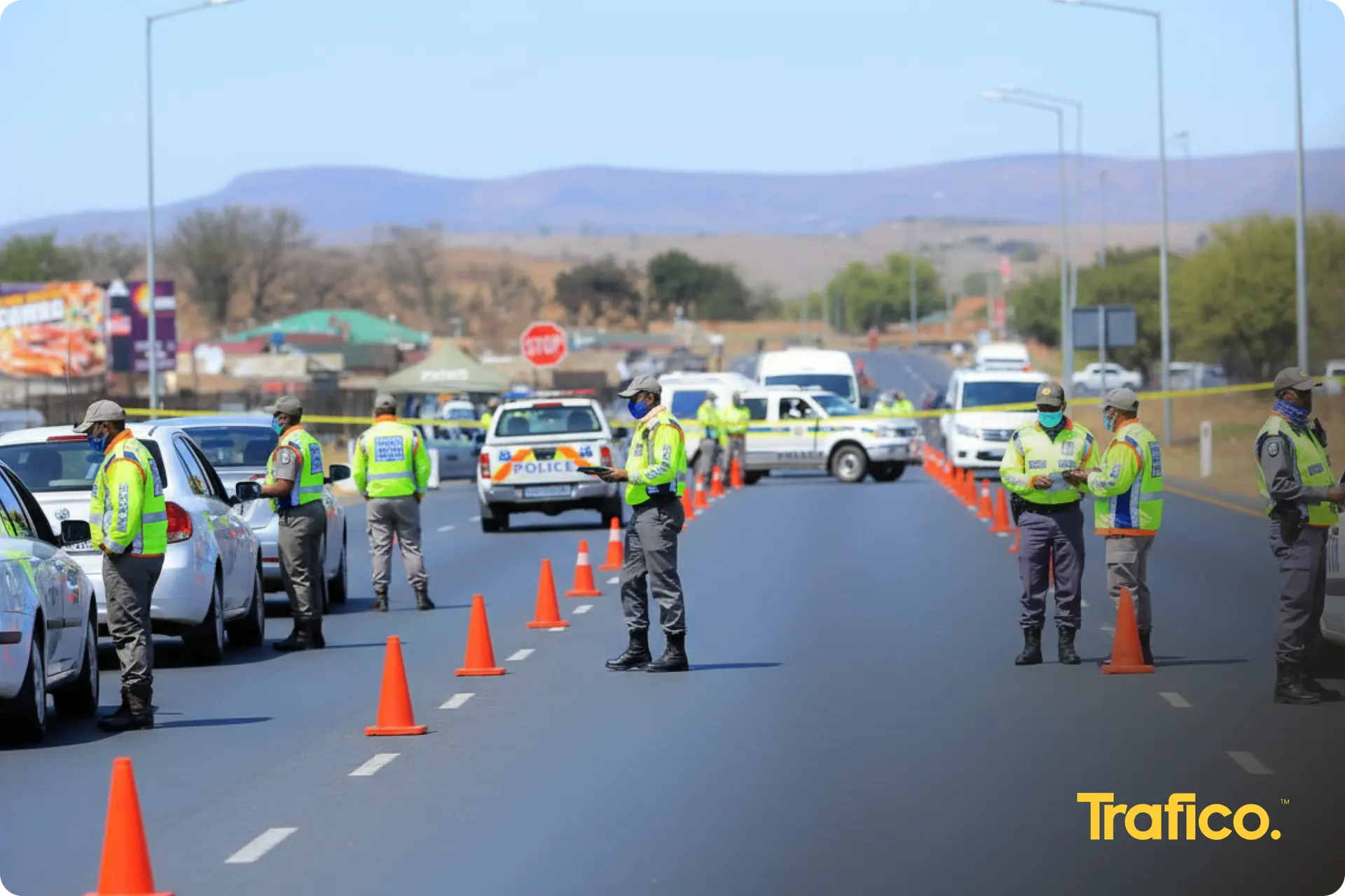 Traffic officers in reflective vests at a roadblock, with cones across the road